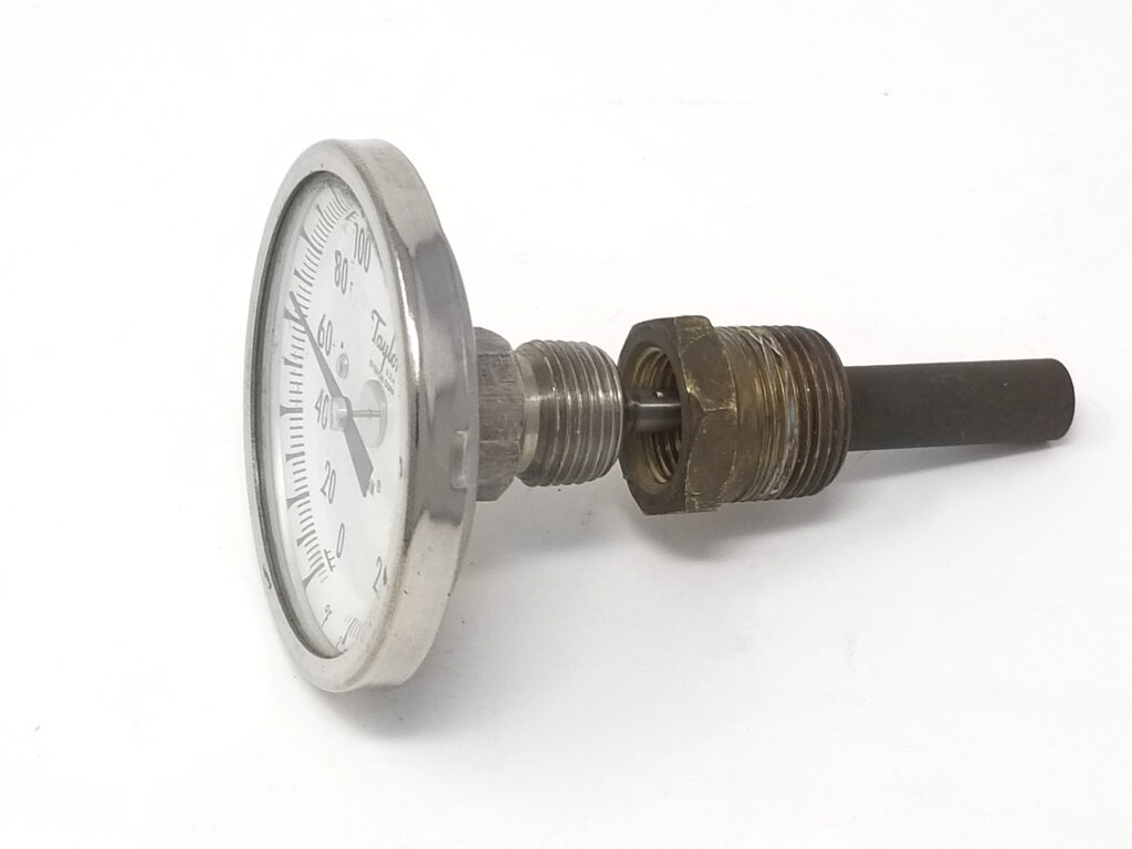 Dial thermometer partially inserted into thermowell